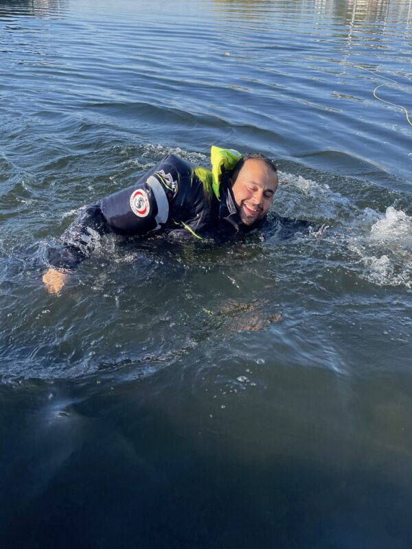 Person im Wasser mit Tauchanzug, lächelt und schwimmt.