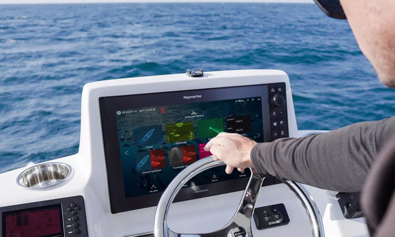 Person nutzt Touchscreen-Navigationssystem auf Boot bei ruhiger See. Moderne Marinetechnik für präzise Kontrolle.